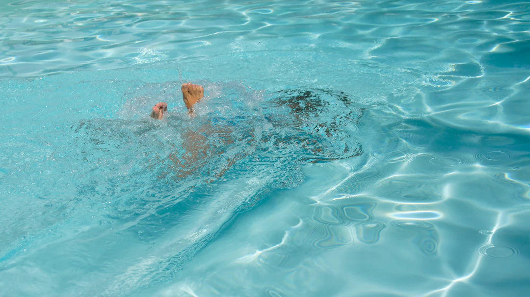 A man swimming in a pool with no shirt on