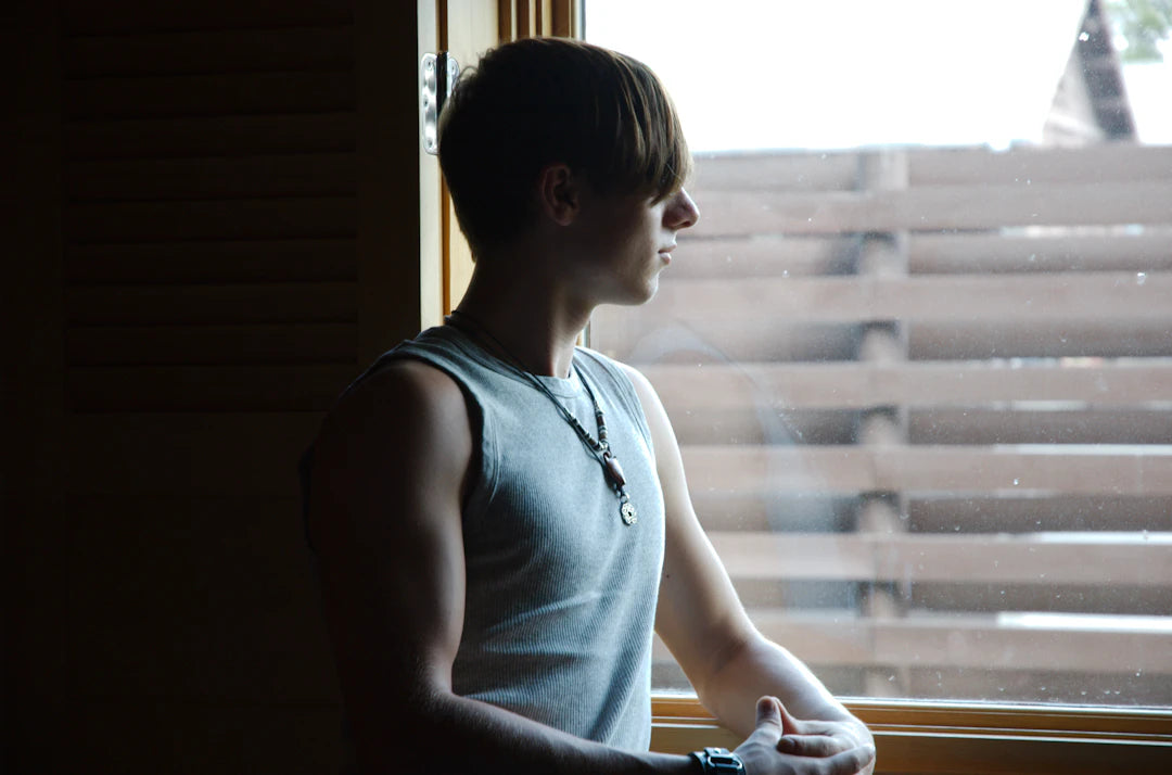 man in blue tank top looking at window