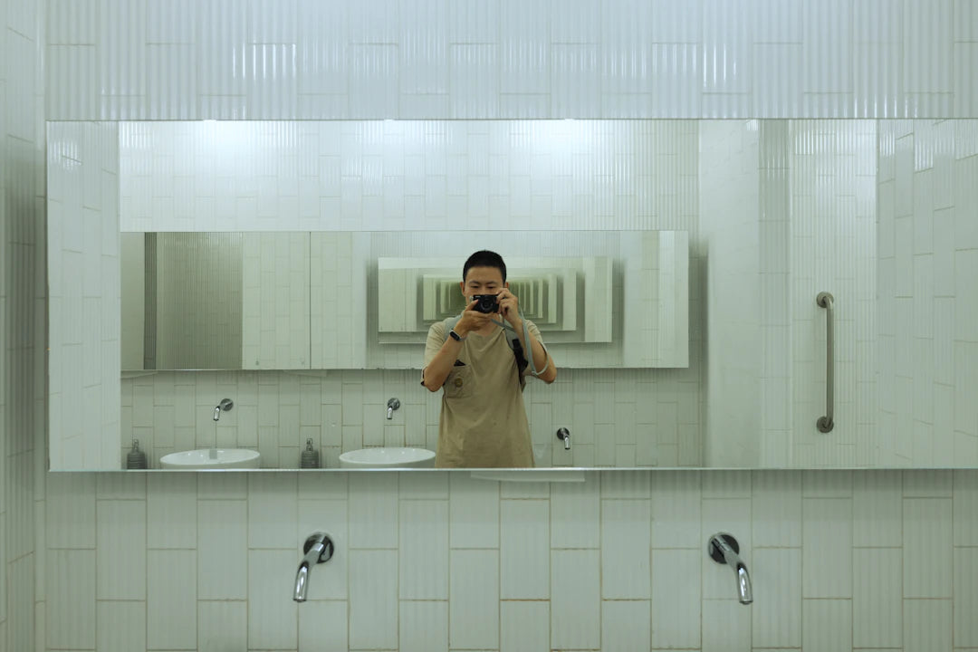 Selfie of a person in a modern white bathroom mirror.