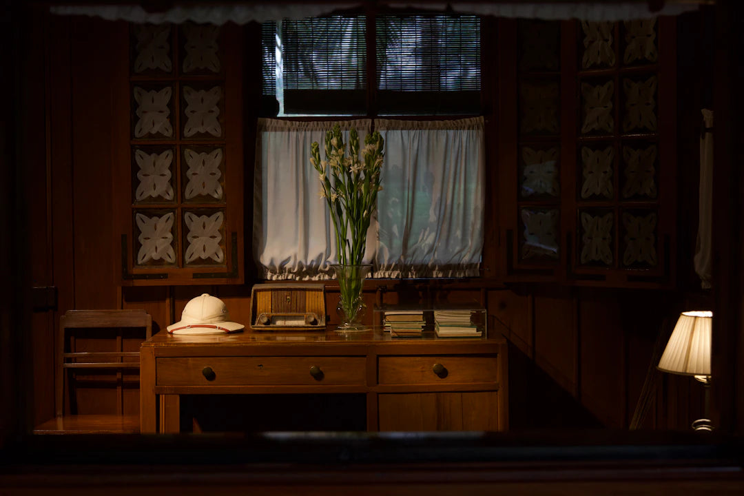 Desk with hat, radio, and flowers in room.
